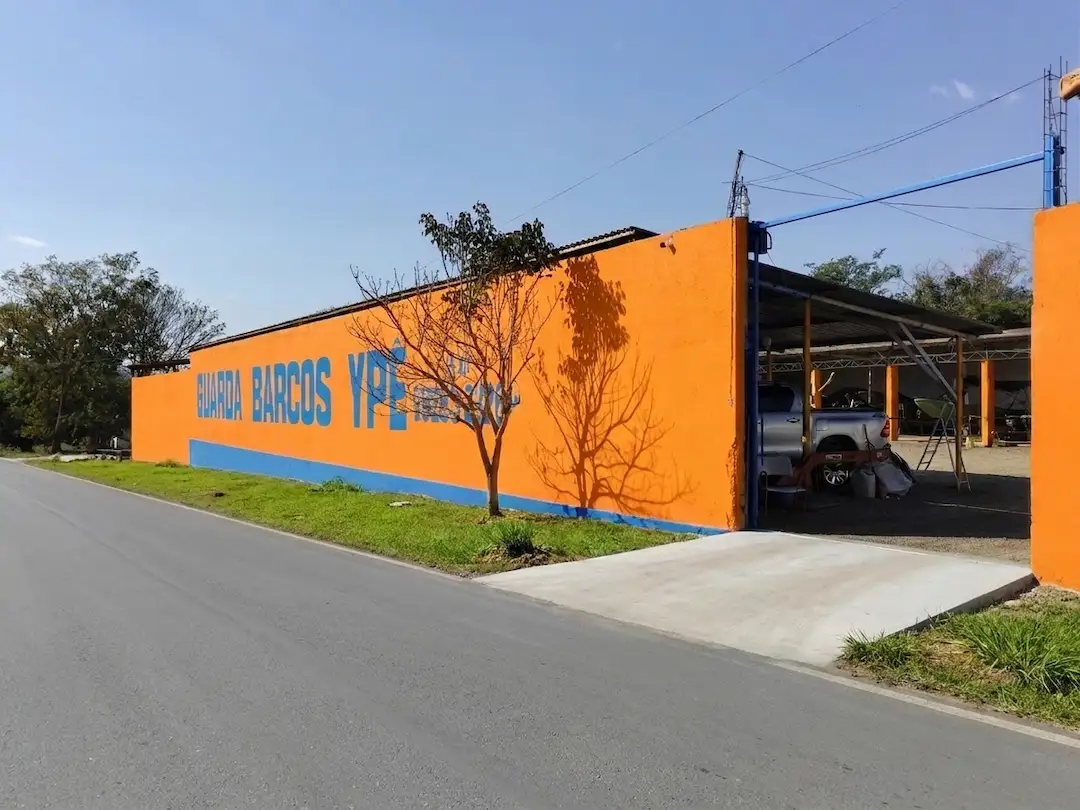 Fachada do Guarda Barcos Ypê, muro amarelo e laranja com acesso cimentado, em Caldas Novas